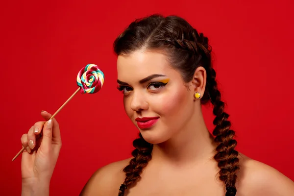 Girl cute funny portrait holding lollipop smiling on red background. Beautiful multicultural Caucasian, girl smiling happy. — Zdjęcie stockowe