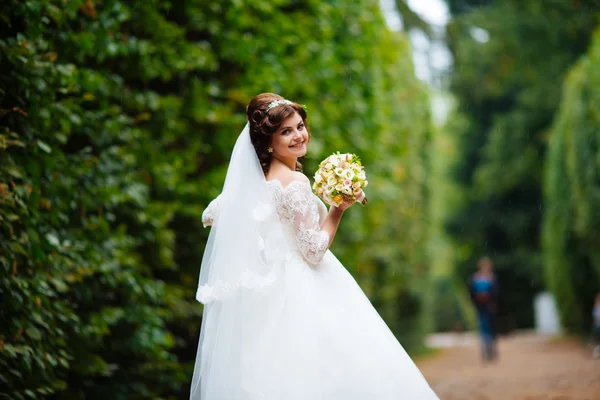 Gorgeous stylish blonde bride in vintage white dress walking in the park — Stock Photo, Image