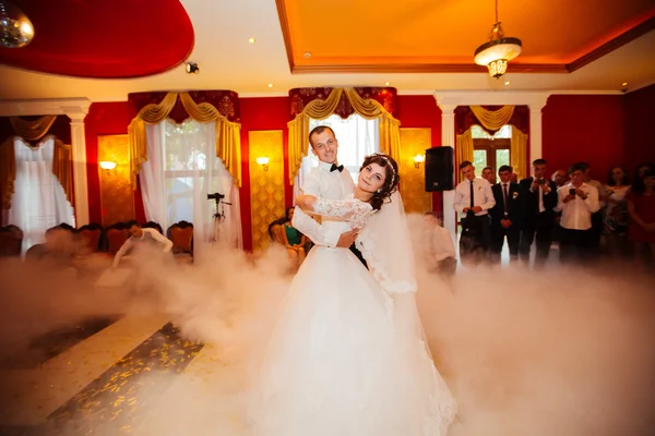 Kiss and dance young bride and groom in dark banqueting hall — Stock Photo, Image