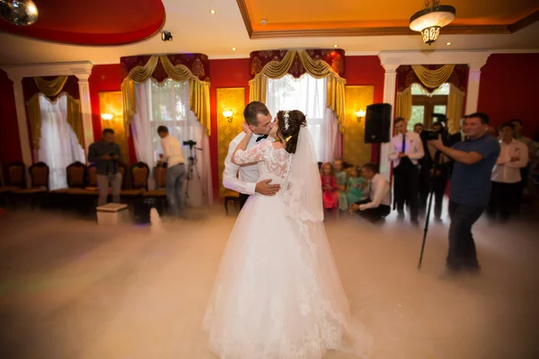 Kiss and dance young bride and groom in dark banqueting hall — Stock Photo, Image