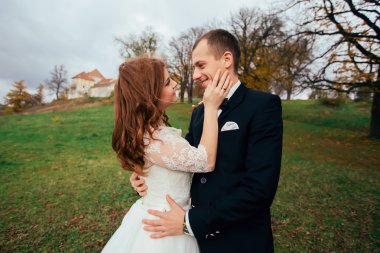 Handsome romantic groom kissing beautiful brunette bride on their happy wedding day on the palace territory