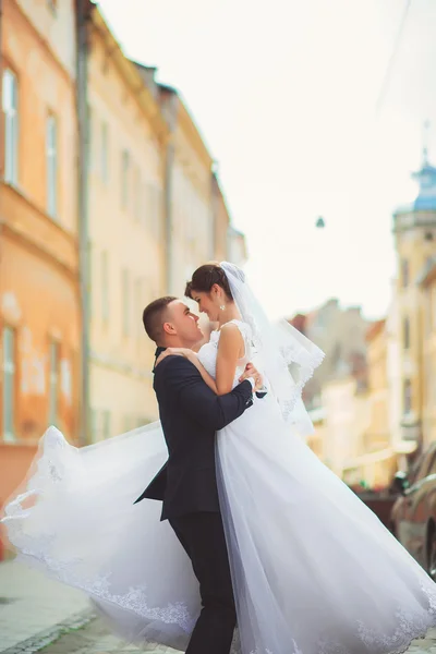 Jeune marié tenant la mariée sur les mains et marchant — Photo