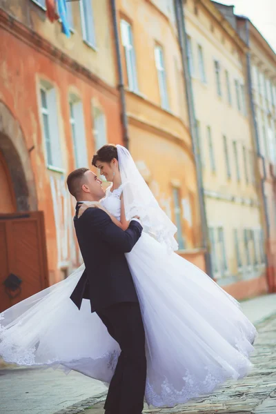 Jovem noivo levantando noiva e beijando — Fotografia de Stock