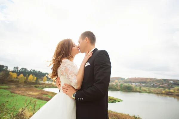 Pareja de boda en panorama de la ciudad y el río. novia con velo largo — Foto de Stock