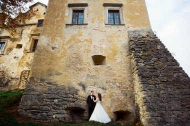 Sarılma ve öpüşme günbatımında sütunlarla eski Barok ghotic Kilisesi önünde bir peri masalı yeni evli çiftin panoramik görünüm