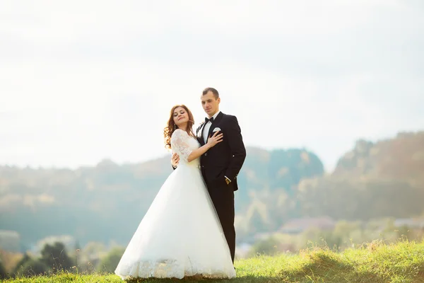 Portrait d'une fille et des couples à la recherche d'une robe de mariée, une robe rose volant avec une couronne de fleurs sur sa tête sur un fond tsvetuschago jardin et le ciel bleu, et ils étreignent et posent — Photo