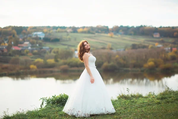 Donna in abito da sposa con un mazzo di fiori bianchi e verde è una radura nella pineta — Foto Stock