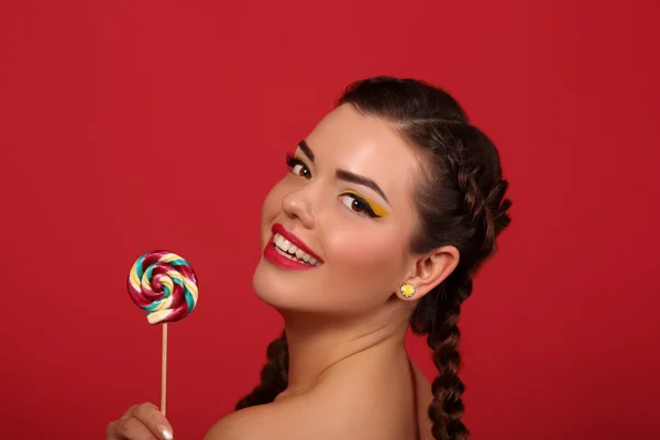 लाल पृष्ठभूमि की पृष्ठभूमि के खिलाफ lollipop साथ खुश युवा महिला — स्टॉक फ़ोटो, इमेज