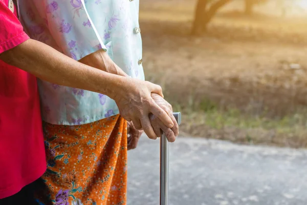 Asian old woman standing with her hands on a walker with daughter\'s hand,Hand of old woman holding a staff cane for helping walkin