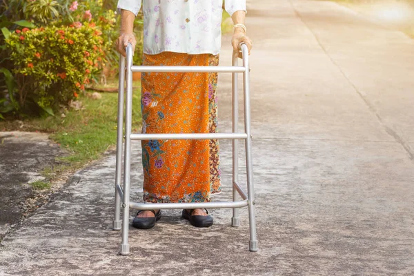 Asian old woman standing with her hands on a walker,Hand of old woman holding a staff cane for helping walkin