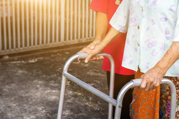 Asian old woman standing with her hands on a walker with daughter\'s hand,Hand of old woman holding a staff cane for helping walkin