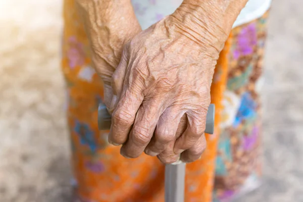Asian old woman standing with her hands on a walking stick ,Hand of old woman holding a staff cane for helping walkin