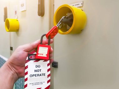 İşlem için kırmızı anahtar kilidi ve etiketi tutan elektriği kesen, elektrik günlüğü için etiket numarasını değiştiren kişi