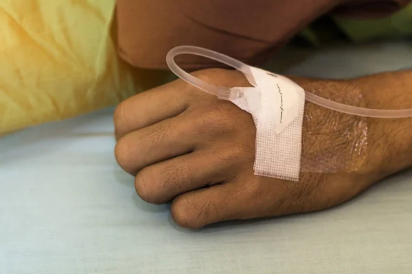 在病人躺在病床上时 将盐水放在手上 滴盐水帮助病人 — 图库照片