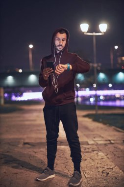 Şehir parkında kapüşonlu sweatshirt 'le antrenman yapan atletik sporcu..