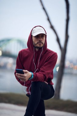 Şehir parkında kapüşonlu sweatshirt 'le antrenman yapan atletik sporcu..