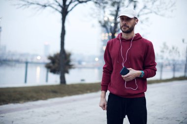 Şehir parkında kapüşonlu sweatshirt 'le antrenman yapan atletik sporcu..