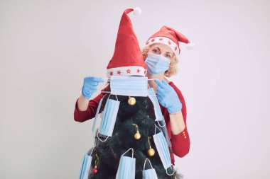 2020 / 2021 virüslü salgın sırasında tıbbi maskelerle Noel ağacını süsleyen kadın..