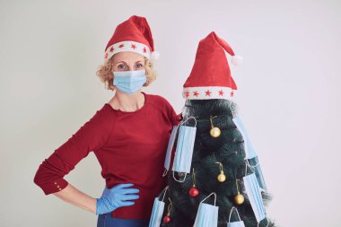 2020 / 2021 virüslü salgın sırasında tıbbi maskelerle Noel ağacını süsleyen kadın..