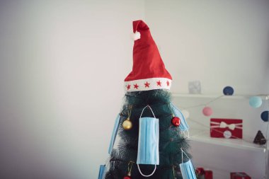 Cerrahi maskelerle süslenmiş Noel ağacı - virüs salgını 2020 / 2021 sosyal mesafesi, tecrit ve karantina izolasyonu.