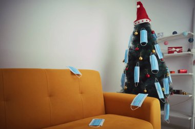Cerrahi maskelerle süslenmiş Noel ağacı - virüs salgını 2020 / 2021 sosyal mesafesi, tecrit ve karantina izolasyonu.