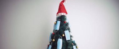 Cerrahi maskelerle süslenmiş Noel ağacı - virüs salgını 2020 / 2021 sosyal mesafesi, tecrit ve karantina izolasyonu.
