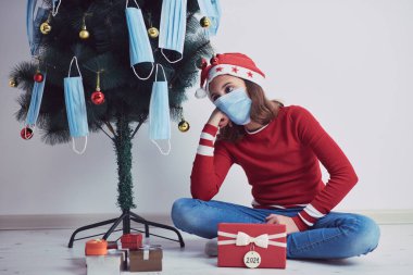 2020 / 2021 yılındaki virüs salgını sırasında küçük bir kız tıbbi maskelerle Noel ağacı süslüyor..