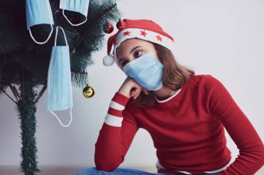 2020 / 2021 yılındaki virüs salgını sırasında küçük bir kız tıbbi maskelerle Noel ağacı süslüyor..