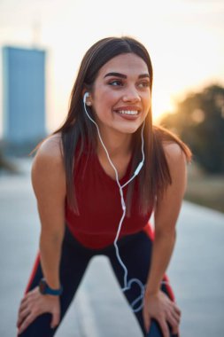 Cep telefonlu modern genç kadın koşu / egzersiz sırasında mola veriyor.