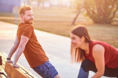 Şehir parkında spor yapan iki genç adam ve kadın..