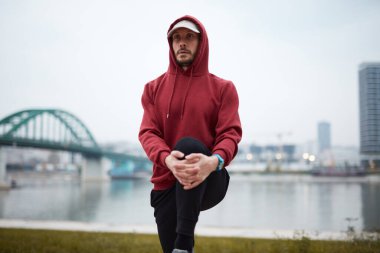 Şehir parkında kapüşonlu sweatshirt 'le antrenman yapan atletik sporcu..