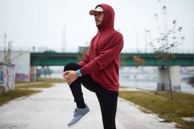 Şehir parkında kapüşonlu sweatshirt 'le antrenman yapan atletik sporcu..