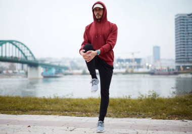 Şehir parkında kapüşonlu sweatshirt 'le antrenman yapan atletik sporcu..