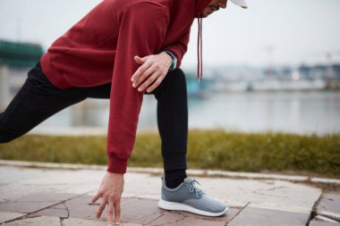 Şehir parkında kapüşonlu sweatshirt 'le antrenman yapan atletik sporcu..