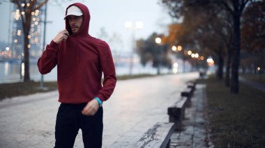 Şehir parkında kapüşonlu sweatshirt 'le antrenman yapan atletik sporcu..