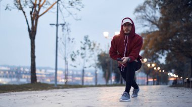 Şehir parkında kapüşonlu sweatshirt 'le antrenman yapan atletik sporcu..