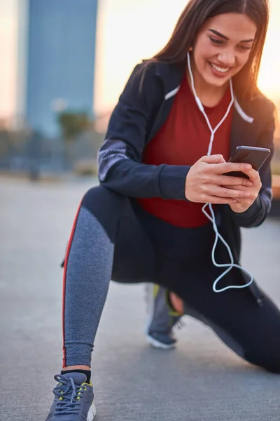 ジョギング 運動中に一時停止する携帯電話を持つ現代の若い女性 — ストック写真