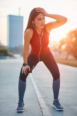 Cep telefonlu modern genç kadın koşu / egzersiz sırasında mola veriyor.