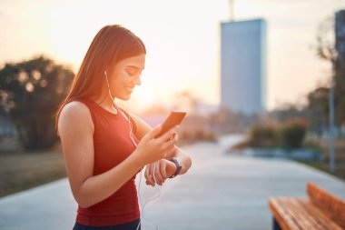 Cep telefonlu modern genç kadın koşu / egzersiz sırasında mola veriyor.