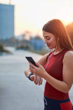 Cep telefonlu modern genç kadın koşu / egzersiz sırasında mola veriyor.