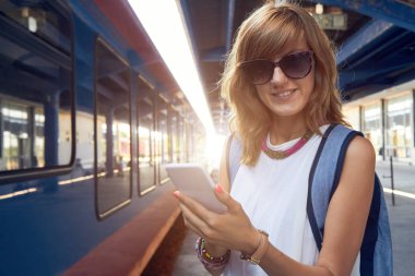 Tren istasyonunda cep telefonu kullanan bir kadın..