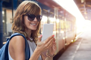 Tren istasyonunda cep telefonu kullanan bir kadın..