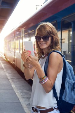 Tren istasyonunda cep telefonu kullanan bir kadın..