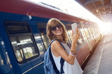 Tren istasyonunda cep telefonu kullanan bir kadın..