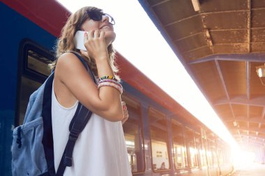 Tren istasyonunda cep telefonu kullanan bir kadın..