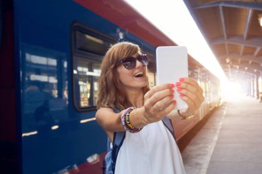 Tren istasyonunda cep telefonu kullanan bir kadın..