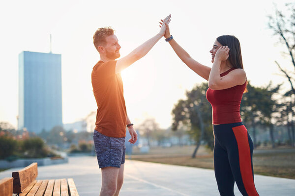 Two young sporty man and woman exercising in urban park.