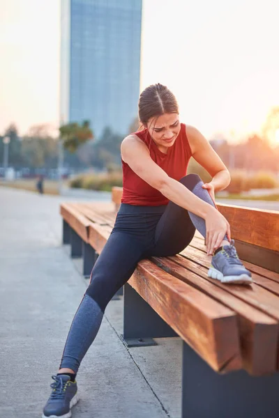 Young sportswoman having pain / injury during exercise and jogging in the park.