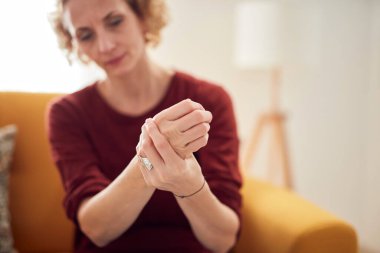 Elleri ağrıyan bir kadın evdeki kanepede oturuyor..