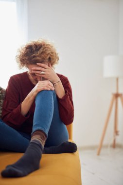 Dizi ve baş ağrısı olan bir kadın evdeki kanepede oturuyor..